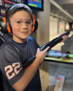 Young guest learning in a supervised indoor shooting range environment with proper safety gear