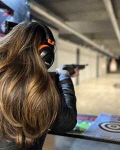 Guest practicing at an indoor shooting lane while wearing proper safety protection
