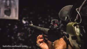 Shooter aiming a Benelli M4 12-gauge shotgun on an indoor range at Gun For Hire in New Jersey
